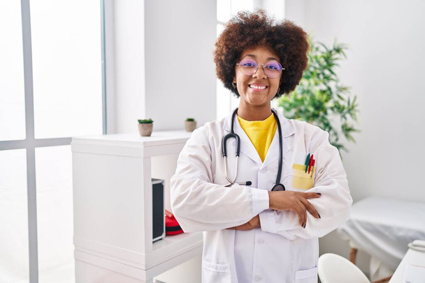 Doktor üniforması giyen Afro-Amerikan kadın klinikte kollarını kavuşturmuş duruyor. - Fotoğraf, Görsel