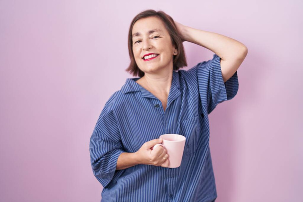 Middle age hispanic woman drinking a cup coffee smiling confident touching hair with hand up gesture, posing attractive and fashionable  - Foto, Imagem