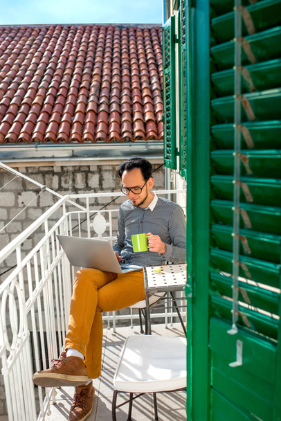 Man met laptop op het balkon - Foto, afbeelding