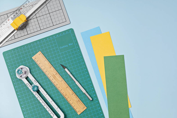 Top view over paper  cut tools, scissors, cutter, cutting mat, and crafted paper objects. DIY trendy project concept. Flat lay - Photo, Image