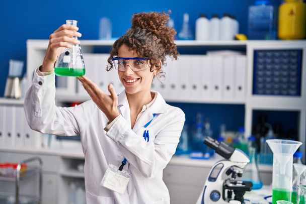 Νεαρή Ισπανίδα επιστήμονας χαμογελώντας σίγουρη μέτρηση υγρών στο εργαστήριο - Φωτογραφία, εικόνα