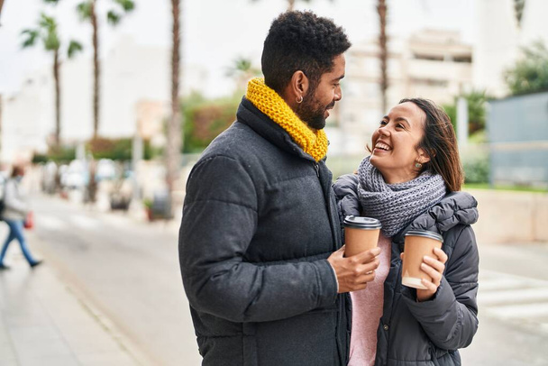Мужчина и женщина улыбаются уверенно, пьют кофе на улице - Фото, изображение