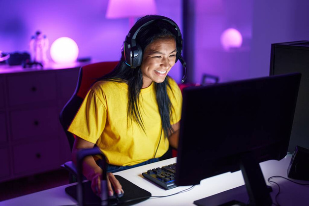 Jovem bela mulher latina streamer jogando videogame usando o computador na sala de jogos - Foto, Imagem