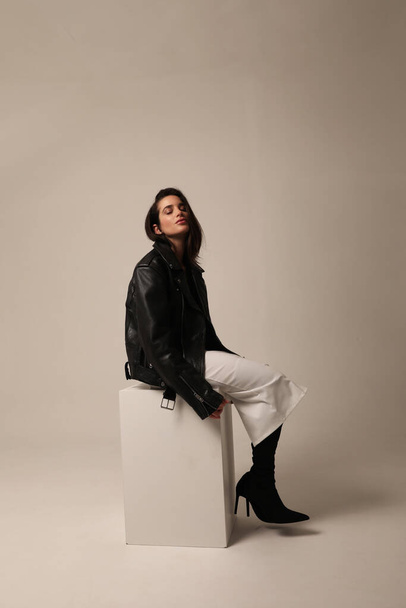Gorgeous young woman posing in studio wearing biker jacket. Vertical mock-up. High quality photo. - Photo, image