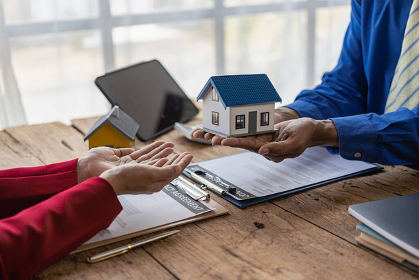 L'agente immobiliare discute i termini del contratto di acquisto di casa e chiede al cliente di firmare documenti per contrarre e consegnare la casa. - Foto, immagini