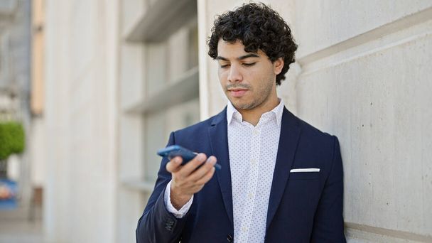 Jonge Latijnse man zakenman met behulp van smartphone op straat - Foto, afbeelding