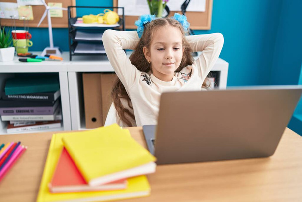 Entzückende kaukasische Studentin mit Laptop entspannt mit den Händen auf dem Kopf im Büro - Foto, Bild