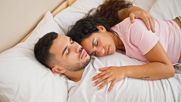 Hombre y mujer pareja acostados en la cama abrazándose el uno al otro durmiendo en el dormitorio - Foto, imagen