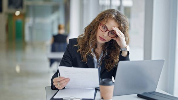 Молода жінка бізнесмен читає документ, підкреслений в офісі - Фото, зображення