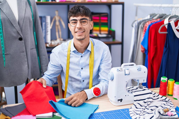 Jonge Spaanse man op maat glimlachend zelfverzekerde kleding in de kleermakerij - Foto, afbeelding