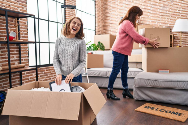 Two women mother and daughter unpacking cardboard box at new home - Foto, Bild
