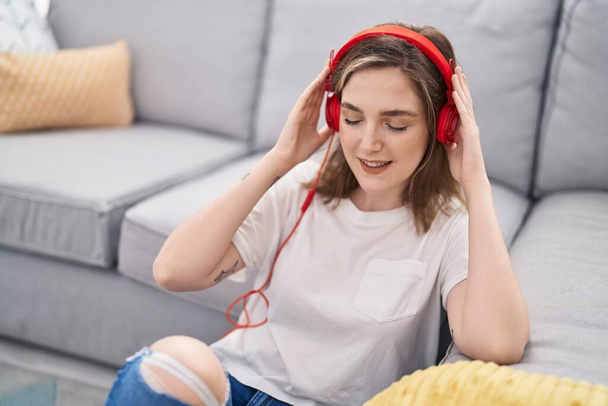 Młoda kobieta słuchająca muzyki siedzącej na podłodze w domu - Zdjęcie, obraz