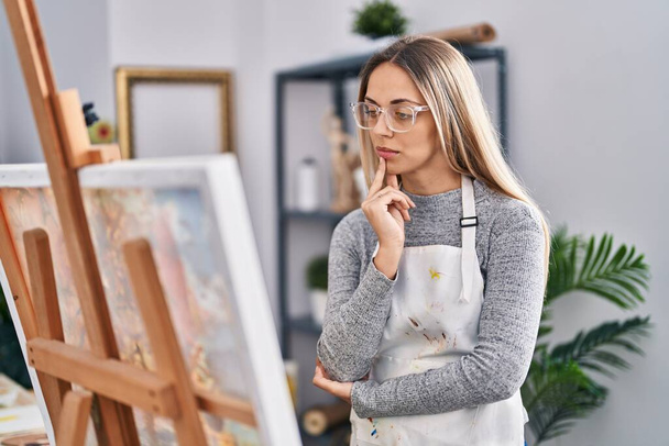Young woman artist looking draw with doubt expression at art studio - Фото, изображение