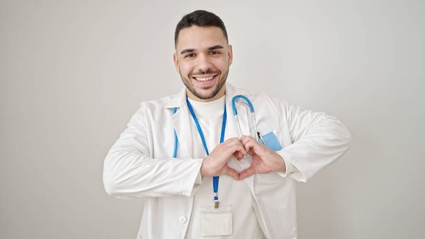 Молодий іспаномовний лікар, посміхаючись, робить жест серця руками над ізольованим білим тлом
 - Фото, зображення