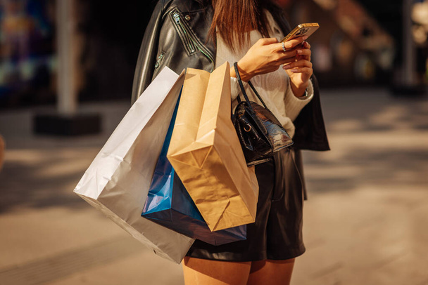 Female person with shopping bags on her armn is checking her phone - Photo, Image