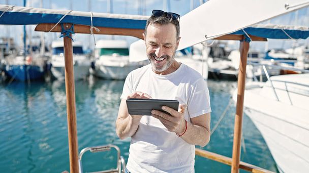 Hombre de mediana edad sonriendo confiado usando touchpad en el barco - Foto, imagen