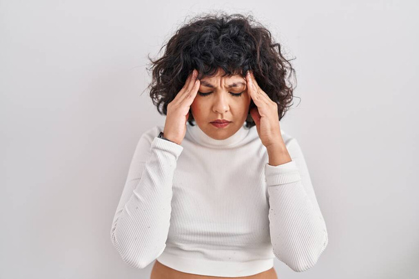 Femme hispanique avec les cheveux bouclés debout sur fond isolé avec la main sur la tête, maux de tête parce que le stress. migraine souffrant.  - Photo, image