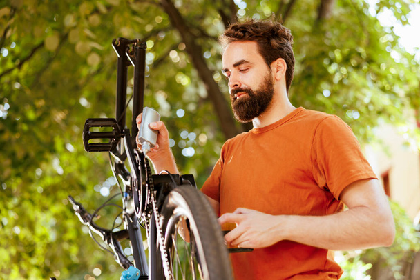 Sportif bir adam bisiklet zincirini yağlamak için özel kayganlaştırıcı kullanıyor. Görüntü, beyaz bir adamın bisiklet zincirini kusursuz bir bisiklet deneyimi için ustalıkla yağladığını gösteriyor.. - Fotoğraf, Görsel