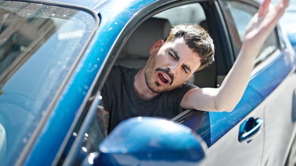 Joven hispano estresado conduciendo coche gritando en la calle - Foto, imagen