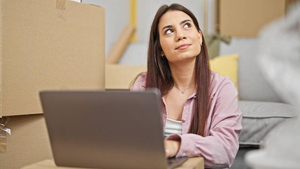 Fiatal gyönyörű spanyol nő használja laptop ül a padlón gondolkodás új otthon - Fotó, kép