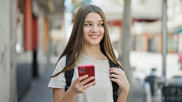 jong mooi meisje student dragen rugzak met behulp van smartphone op straat - Foto, afbeelding