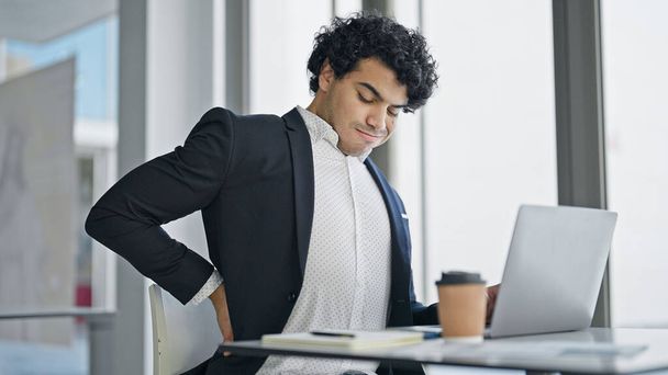 Nuori latinomies liike-elämän työntekijä käyttää kannettavaa tietokonetta kärsimystä selkäkipu toimistossa - Valokuva, kuva