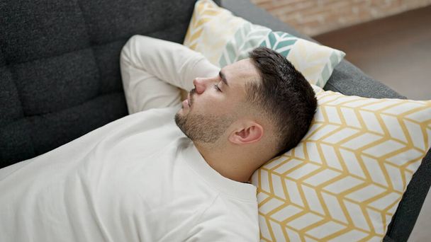 Joven hispano tumbado en un sofá durmiendo en casa - Foto, imagen