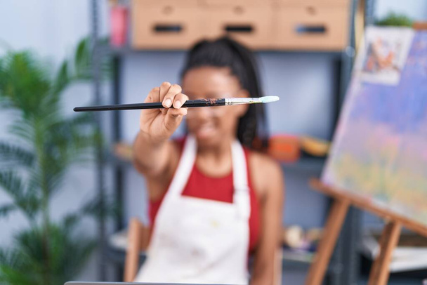 African american woman holding paintbrushe at art studio - Photo, Image