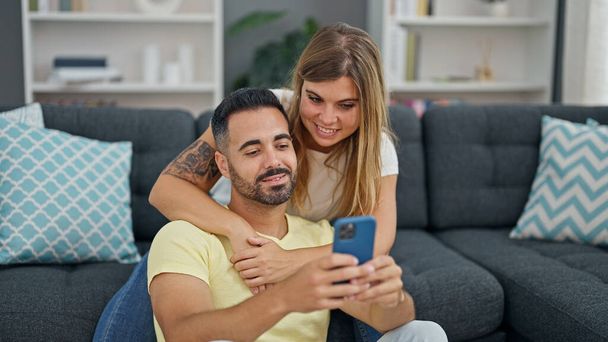 Чоловік і жінка пара, використовуючи смартфон, сидячи на дивані вдома
 - Фото, зображення