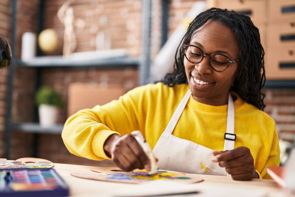 Afrykańska amerykanka artystka uśmiecha się pewnie mieszając kolor w studio sztuki - Zdjęcie, obraz
