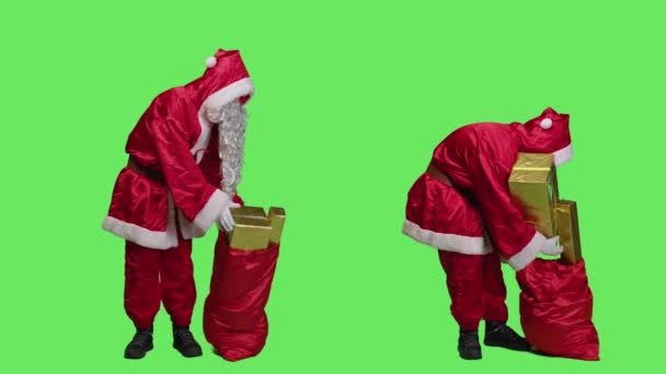 Ojciec Boże Narodzenie niesie torbę z prezentami na święta Bożego Narodzenia, dostarczając prezenty i zabawki dla dzieci na całym świecie. Mężczyzna przedstawiając Mikołaja i trzymając czerwony worek z paczkami. - Materiał filmowy, wideo