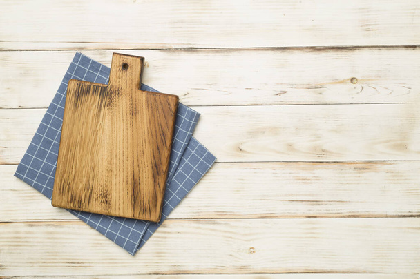 Cutting board with towel on wooden background, top view. - Photo, Image