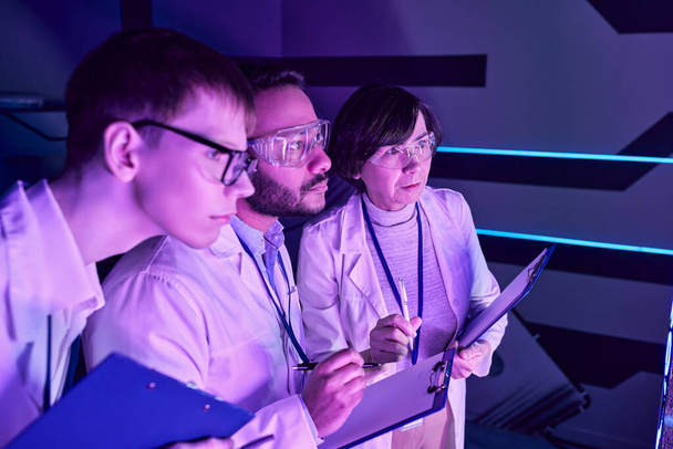 Analisi futuristica: tre scienziati approfondiscono lo studio dei dispositivi nel Neon-Lit Science Center. - Foto, immagini