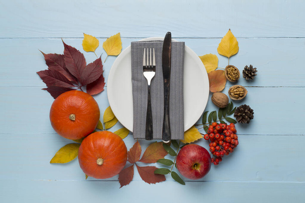 Teller mit Besteck, Serviette und Herbstdekor auf Holzgrund, Draufsicht. Erntedank-Tisch gedeckt? - Foto, Bild