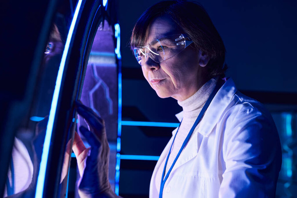 tulevaisuuteen ajatteleva keski-ikäinen nainen tiedemies katselee innovatiivista laitetta löytökeskuksessa - Valokuva, kuva