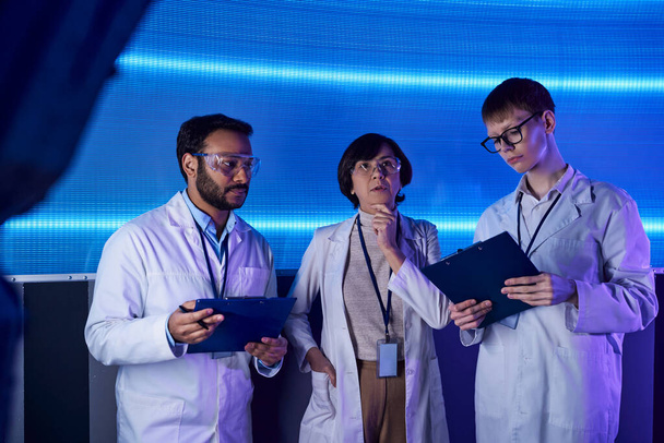 futuristic concept, multiethnic team of scientists with clipboards working in innovation hub - Photo, Image