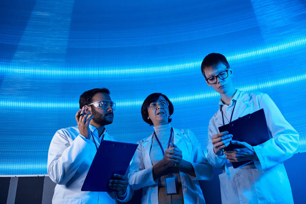 cientistas multiétnicos com pranchetas trabalhando em tecnologias futuristas no centro de ciências - Foto, Imagem