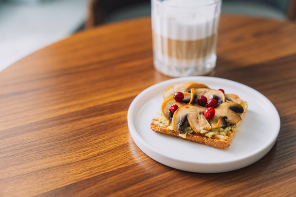 Τοστ με μανιτάρια και cranberries σε λευκό πιάτο με καφέ. - Φωτογραφία, εικόνα