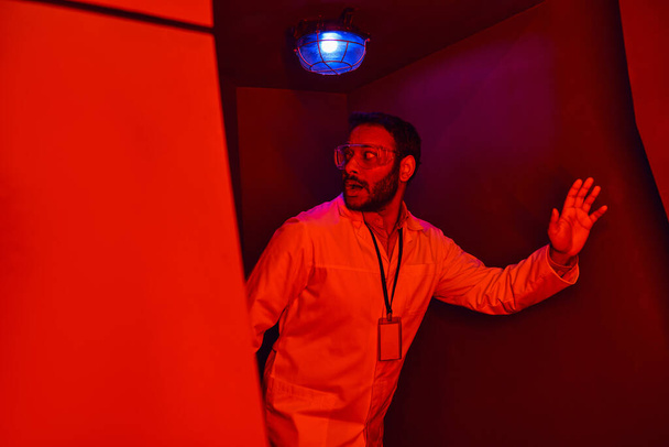 άγνωστο φαινόμενο, φοβισμένος ινδός επιστήμονας κοιτάζοντας μακριά στο κόκκινο φως νέον στον κόμβο καινοτομίας - Φωτογραφία, εικόνα