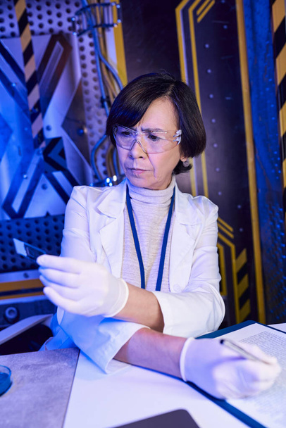 исследуя вселенную, женщина-ученый в очках смотрит на лакмусовую бумагу в экспериментальной лаборатории - Фото, изображение