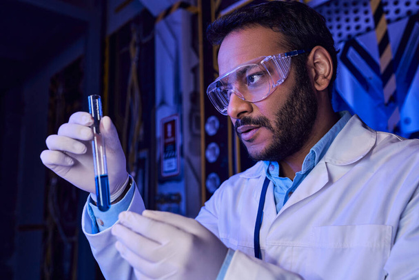 tulevaisuuteen ajatteleva intialainen tiedemies suojalaseissa, joilla on nestemäinen näyte koeputkessa, futuristinen laboratorio - Valokuva, kuva