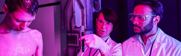 scienziato in possesso di provetta con campione di sangue alieno vicino al collega indiano in laboratorio futuristico, banner - Foto, immagini