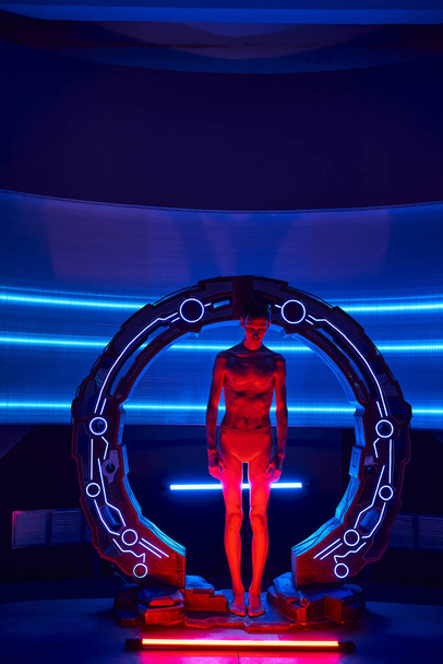 extraterrestrial humanoid standing in neon-lit innovative device in futuristic lab, full length - Photo, Image