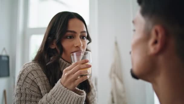 Smiling woman drinking glass of juice at home close up. Latina lady enjoying morning beverage laughing of husband jokes. Positive man having fun with wife. Romantic couple weekend lazy lifestyle - Footage, Video