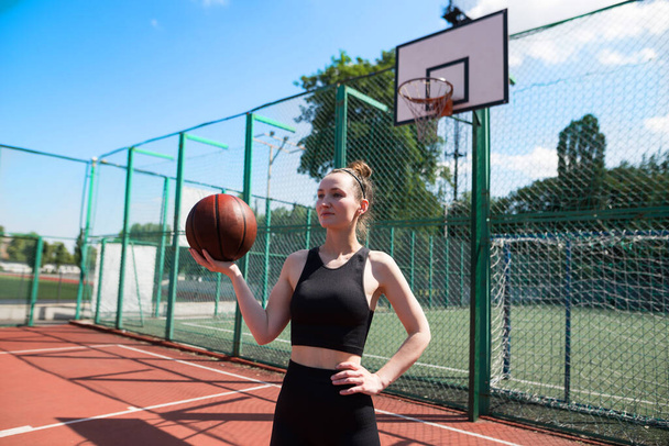 Giovane ragazza sportiva con una pallacanestro sul campo da basket all'aperto, weekend attivo. - Foto, immagini