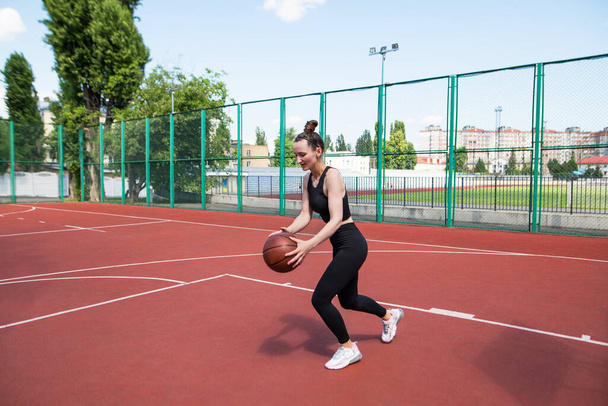 Atletik basketbolcu basketbol sahasında topu sürüyor. Basketbol, oyun, eğlence, açık hava stencilling. - Fotoğraf, Görsel