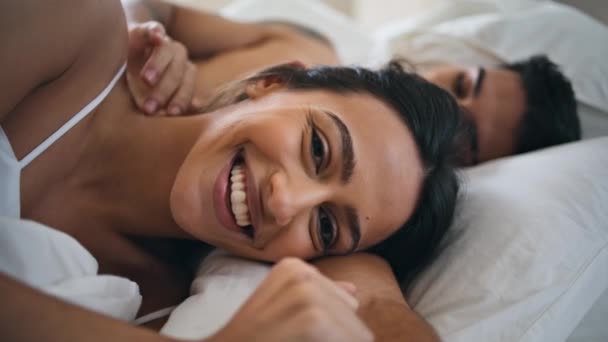 Intimate lovers laying together at morning bedroom closeup. Loving husband touching wife gently. Smiling woman looking camera portrait. Sweethearts enjoying time together at cozy home. Love concept - Footage, Video