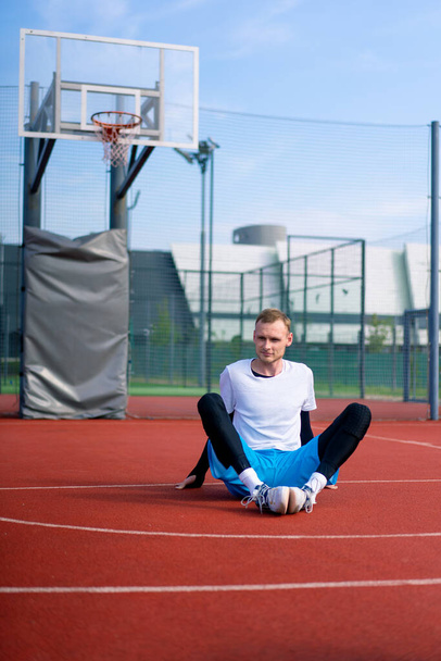 jogador de basquete cara alto senta-se em um campo de basquete fora antes do início da prática - Foto, Imagem