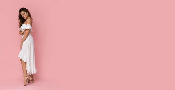 Molto attraente giovane donna in abito bianco su sfondo rosa isolato. - Foto, immagini