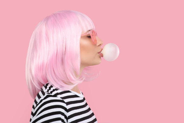 Beautiful woman in sunglasses blowing bubble gum on pink background, space for text - Foto, immagini